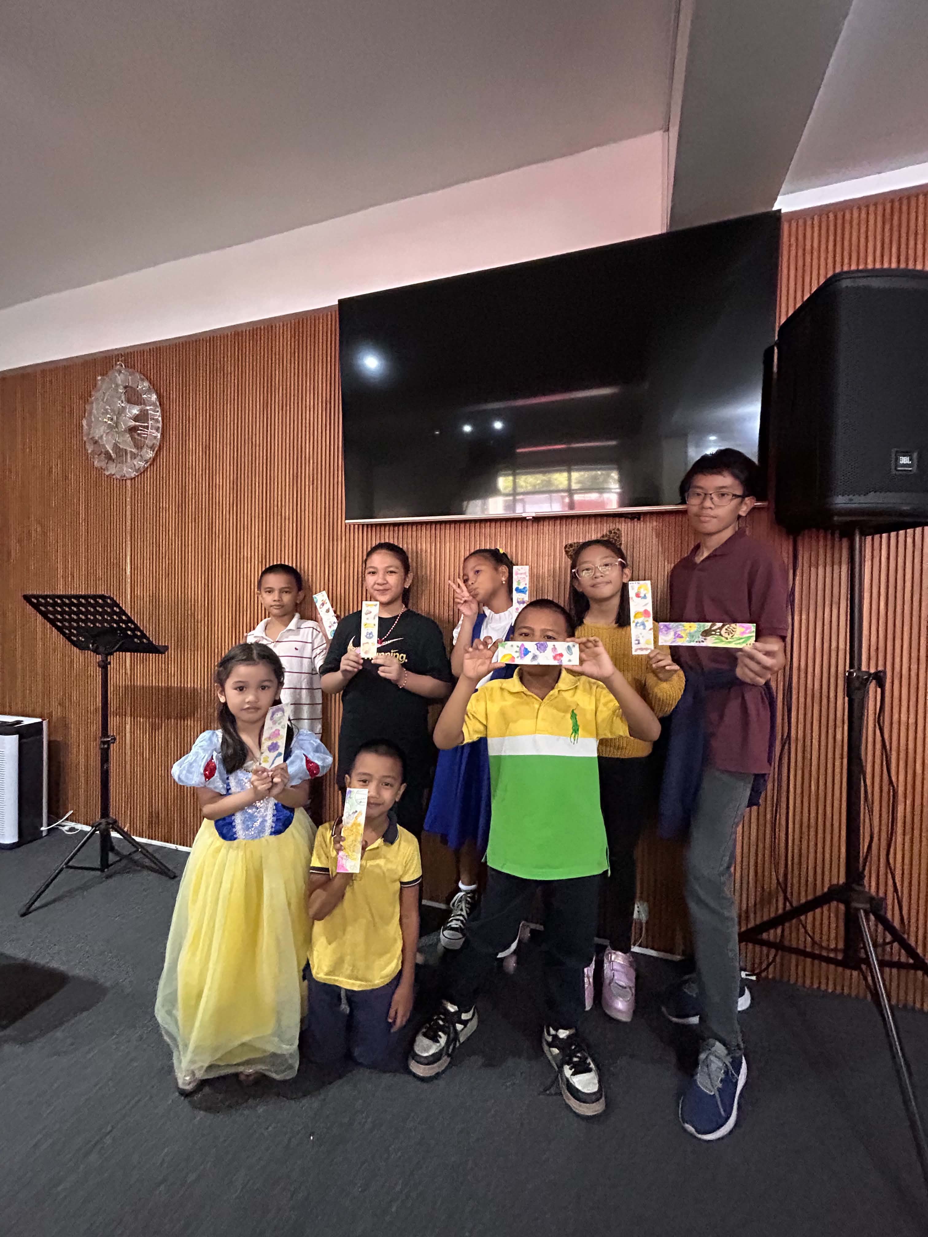 Kids and teens holding up their painted bookmarks
